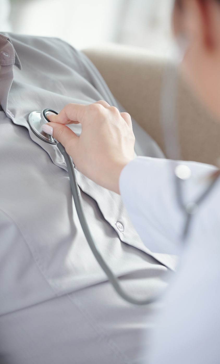 Skilled nurse checking resident's heart with stethoscope